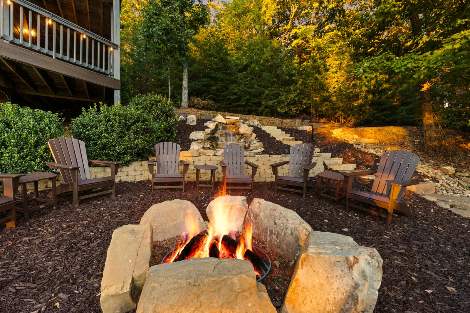 The fire pit lit, ringed by Adirondack chairs