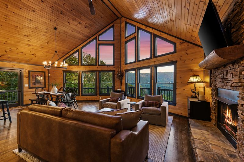 The great room at dusk, with its wall of windows and the fireplace lit