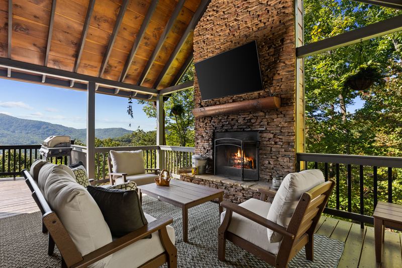 The front porch fireplace, TV and lounge chairs